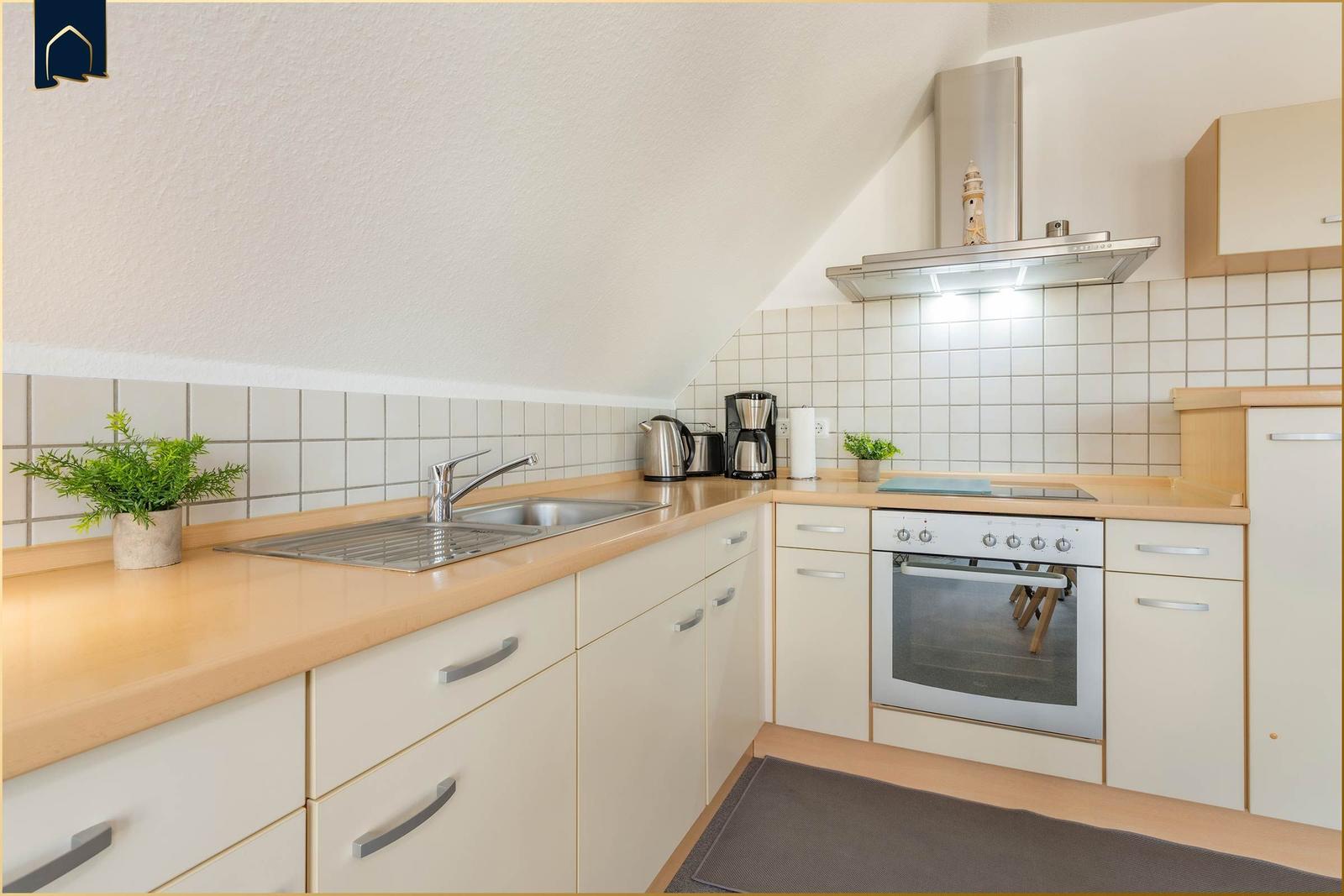 Küche mit Arbeitsfläche, Spüle, Herd und Dunstabzug.