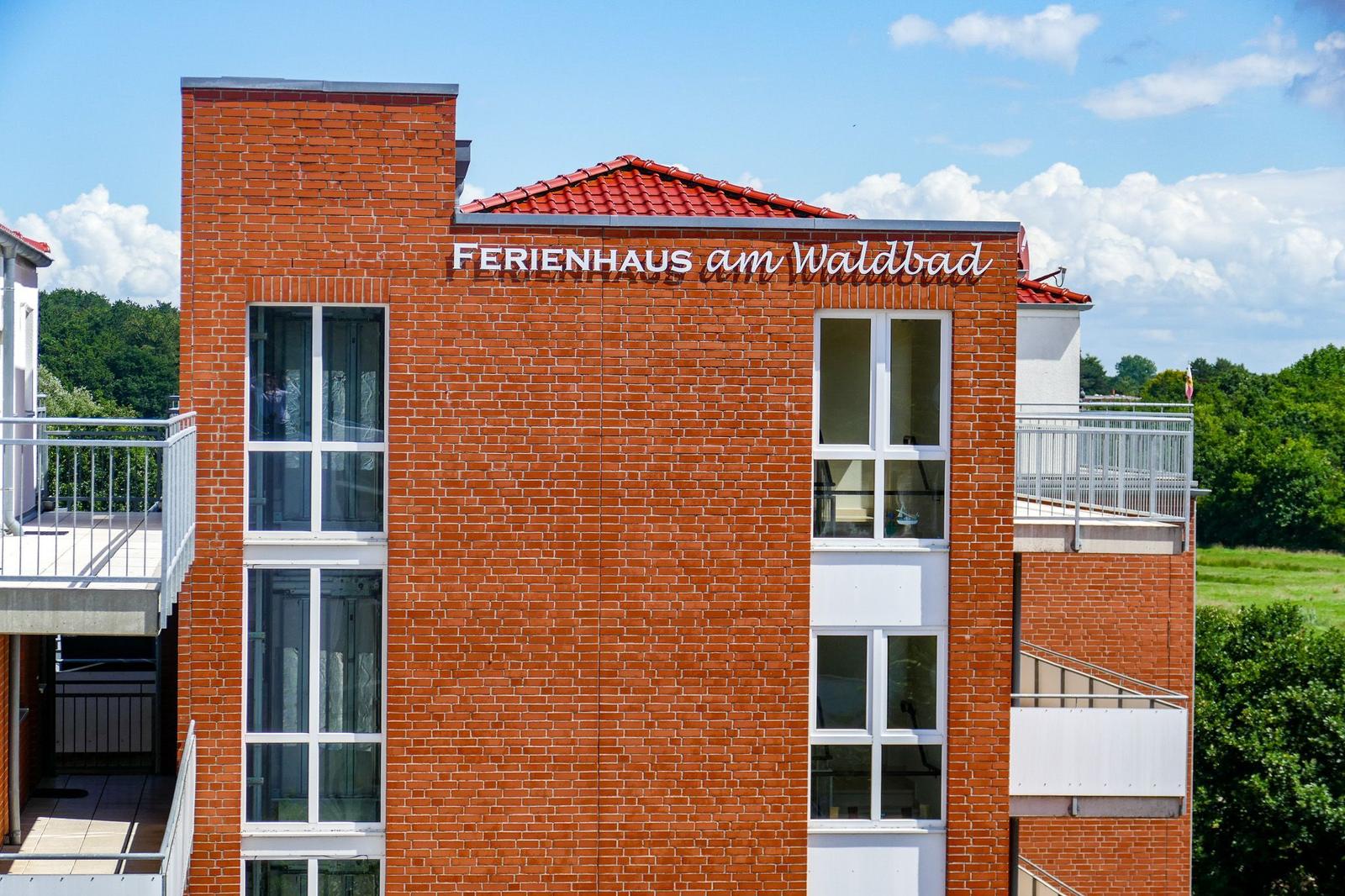 Ferienhaus am Waldbad mit rotem Ziegeldach und Balkonen