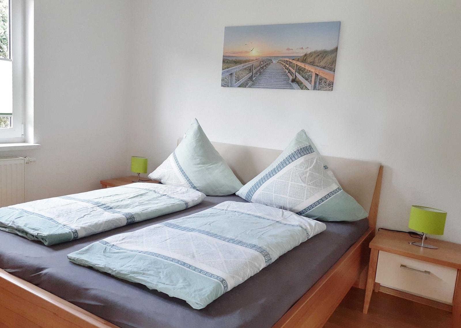 Zimmer mit Doppelbett, zwei Nachttischen und Wandbild