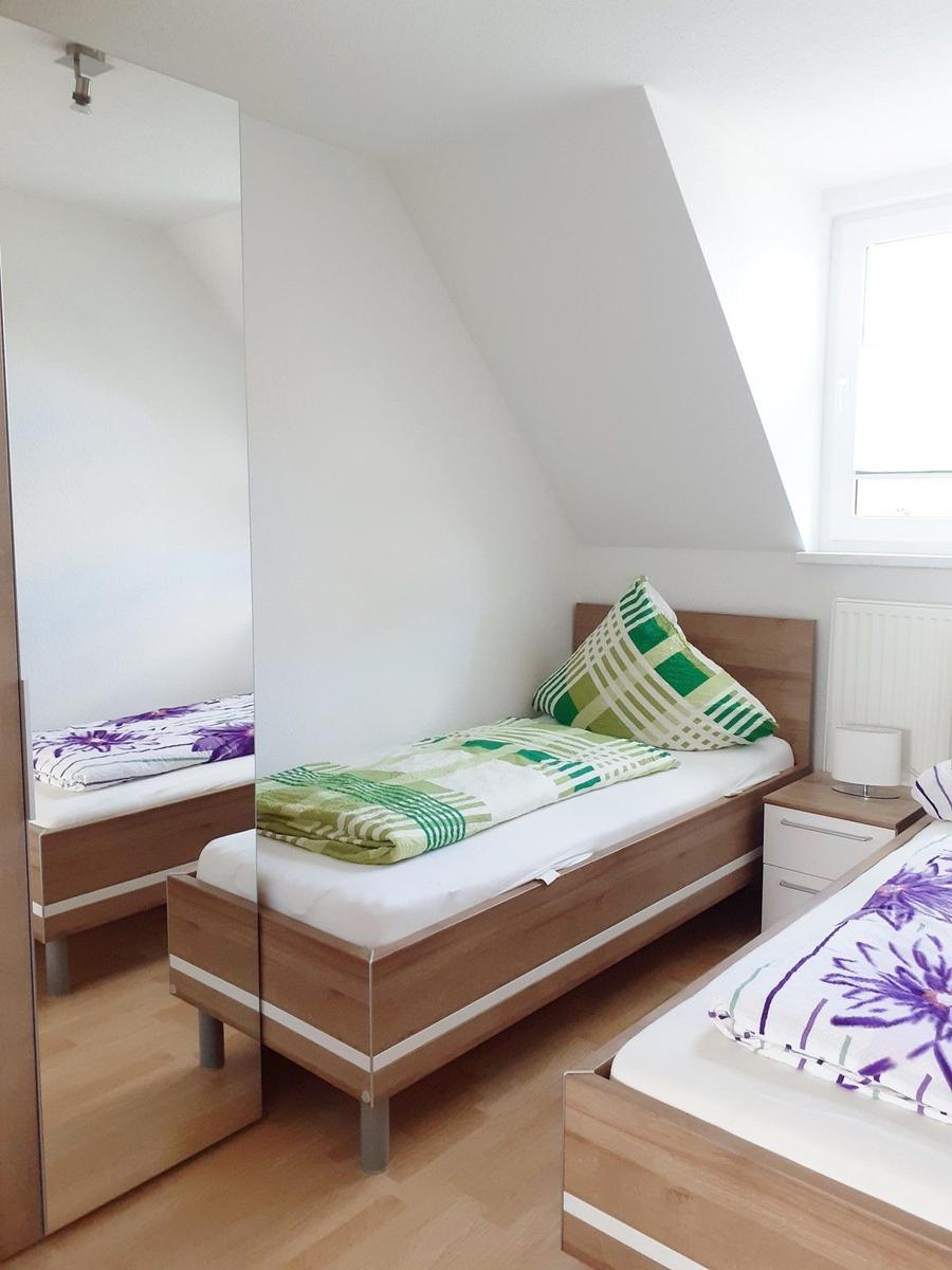 Schlafzimmer mit zwei Betten, Spiegelschrank und Fenster