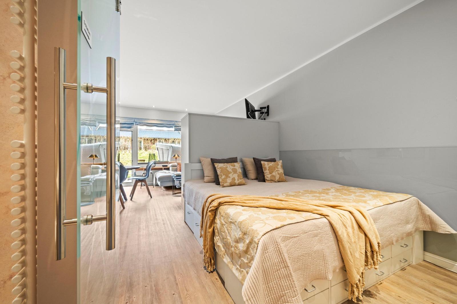 Schlafzimmer mit Bett, Wand-TV und Sicht auf Terrasse