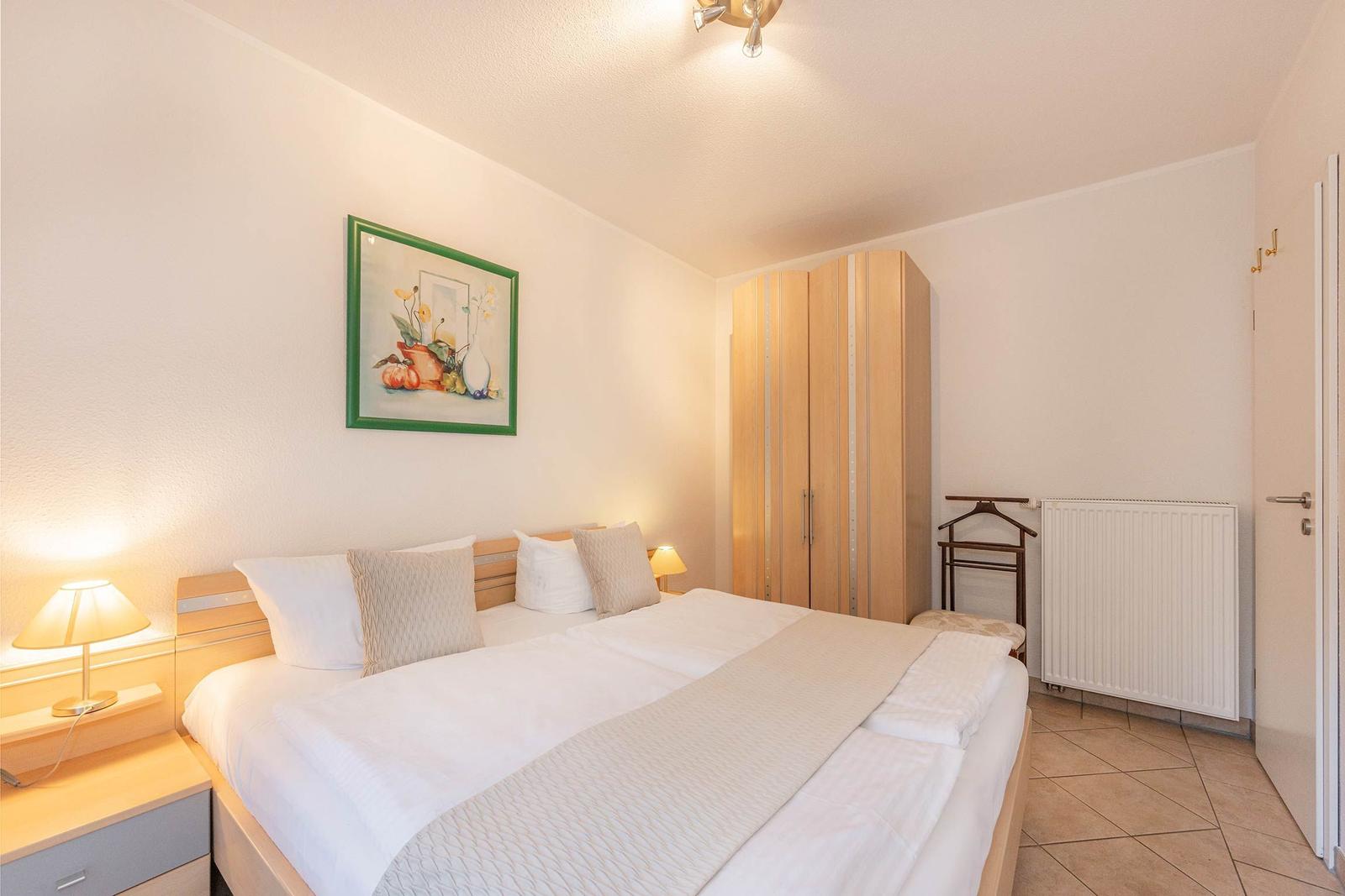 Schlafzimmer mit Doppelbett, Kleiderschrank und Nachttisch mit Lampe.