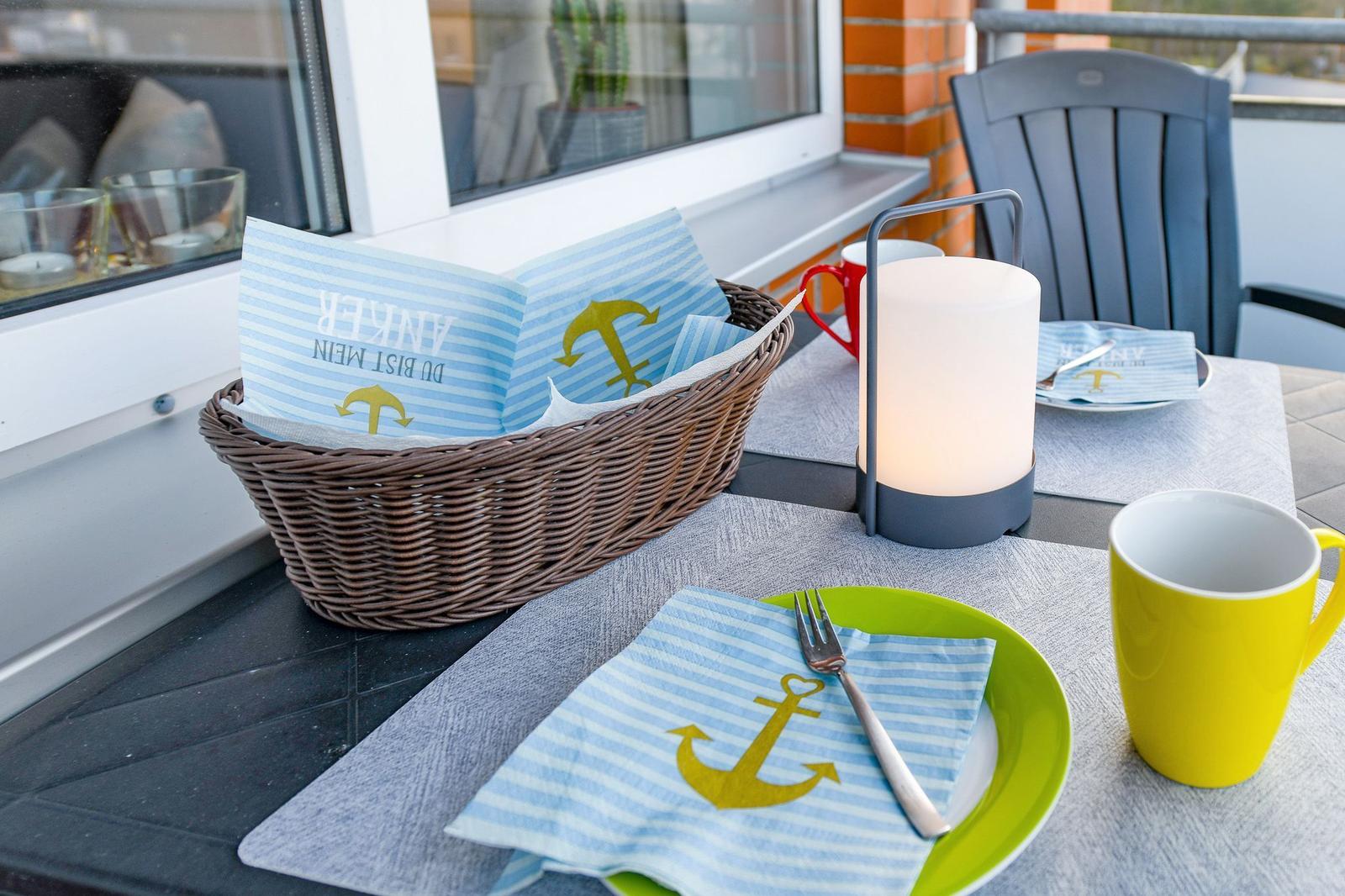 Tisch auf Balkon mit Platzset, Korb und Lampe