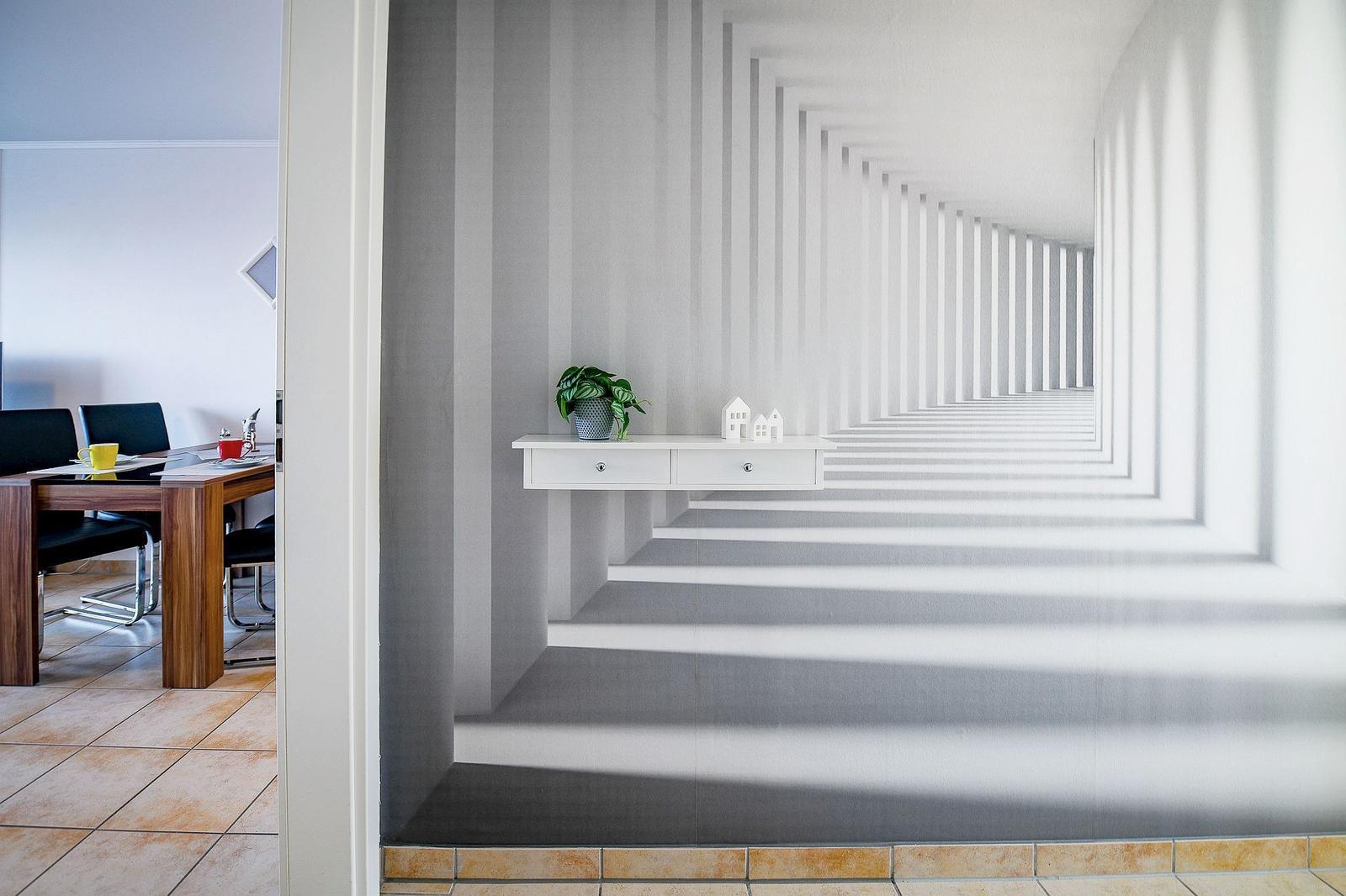 Flur mit Wandtapete, Schrank und Pflanze. Durchgang zu Esszimmer mit Tisch und Stühlen.