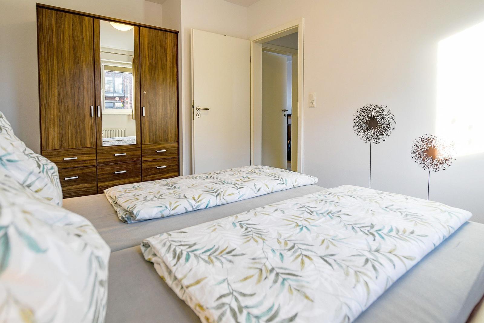Schlafzimmer mit Doppelbett, Kleiderschrank und Wanddekoration.