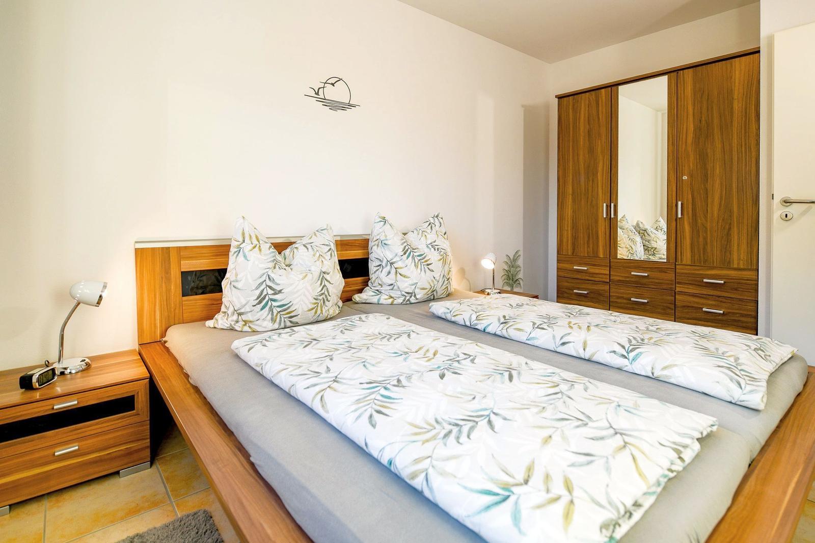 Schlafzimmer mit Doppelbett, Nachttisch und Kleiderschrank.