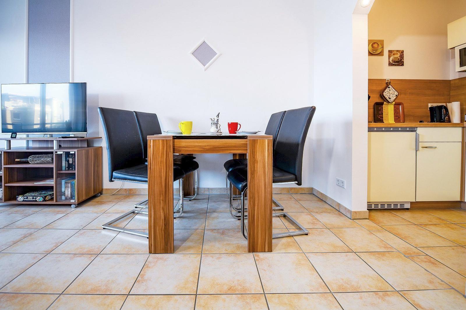 Essbereich mit Tisch, Stühlen und TV. Küche mit Arbeitsfläche und Küchenschränken.