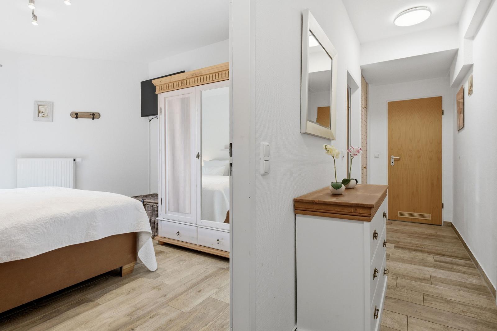 Schlafzimmer mit Bett, Kleiderschrank und Flur mit Schminktisch.