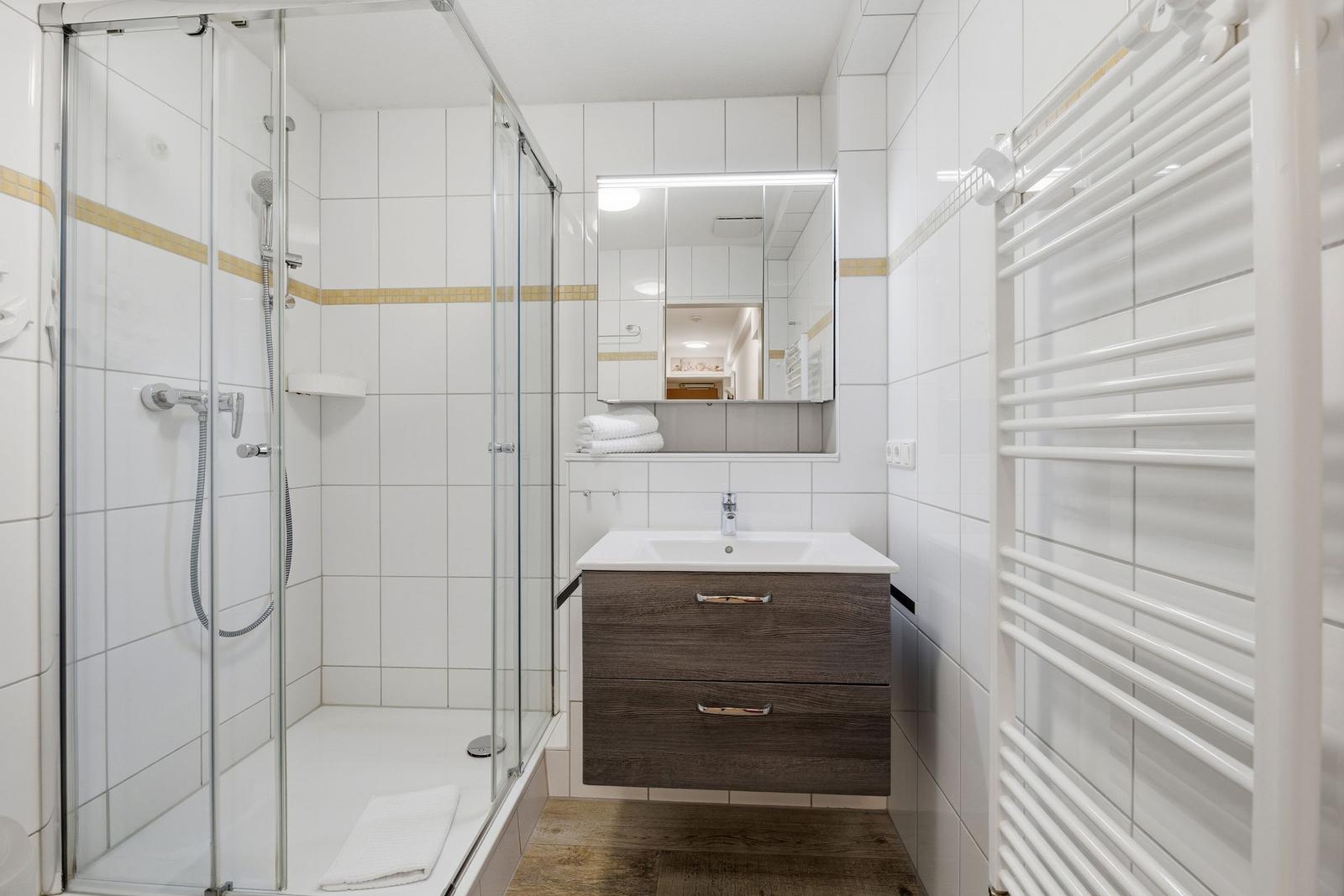 Badezimmer mit Dusche, Waschbecken und Heizkörper