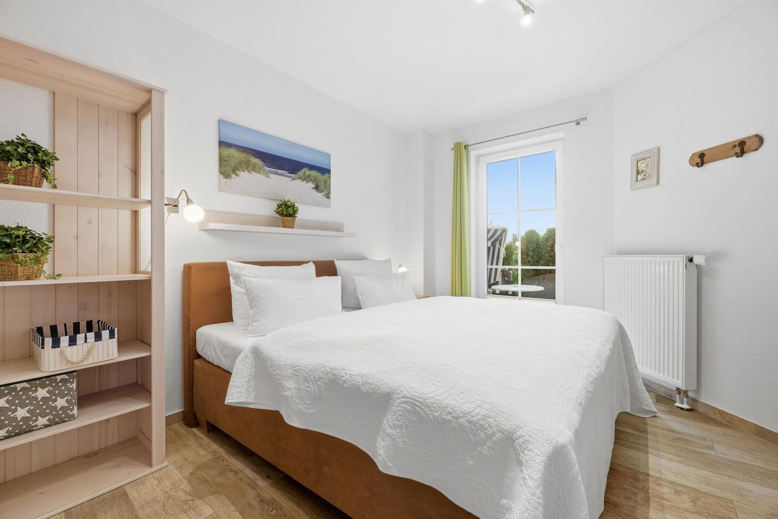 Schlafzimmer mit Bett, Regal und Fenster zum Garten.