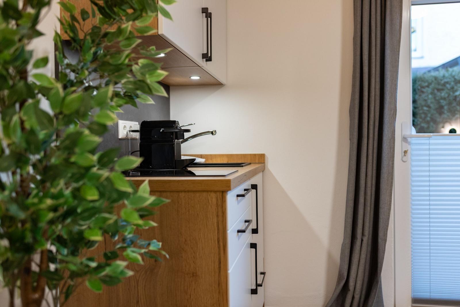 Küche mit Holzoberfläche, schwarzer Kaffeemaschine und Fenster mit Jalousie.