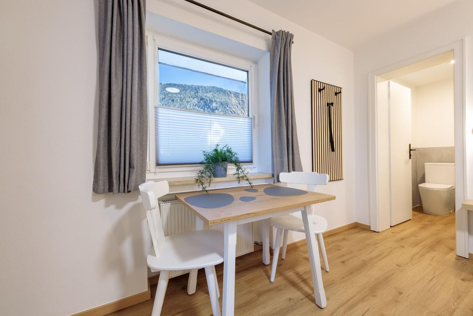 Essbereich mit Tisch, zwei Stühlen und Blick auf die Berge.