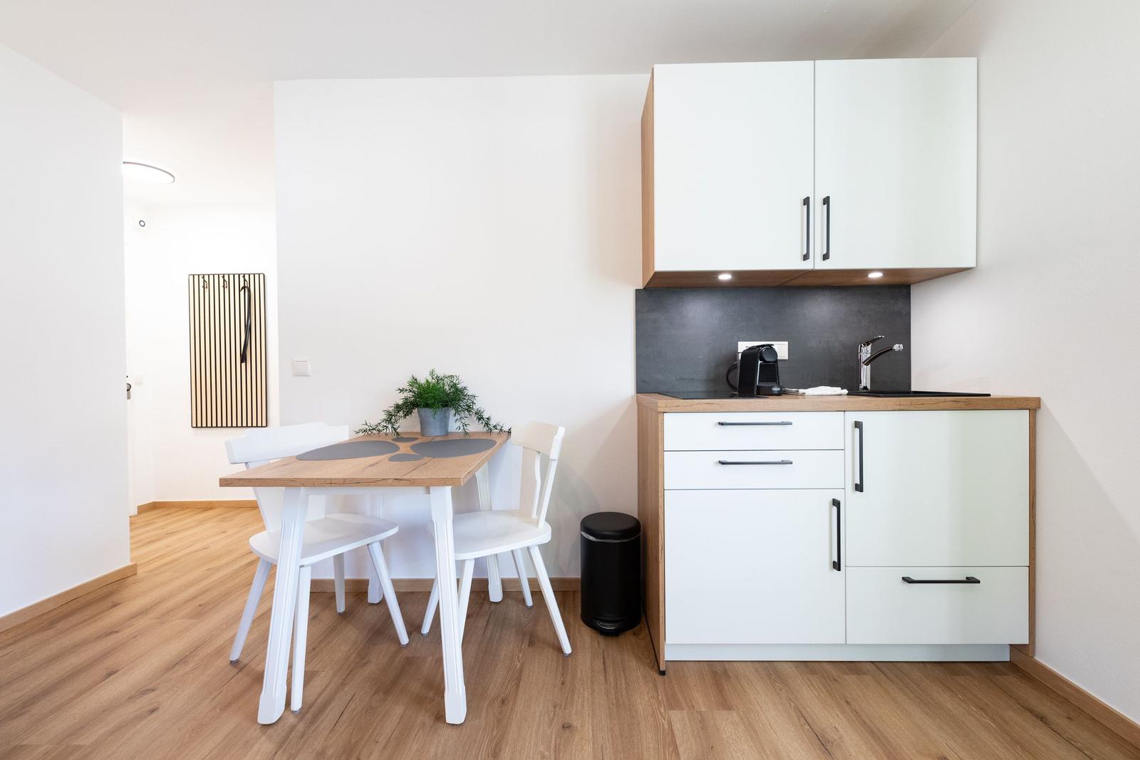 Küche mit Essplatz, Holzfußboden und weißen Schränken.