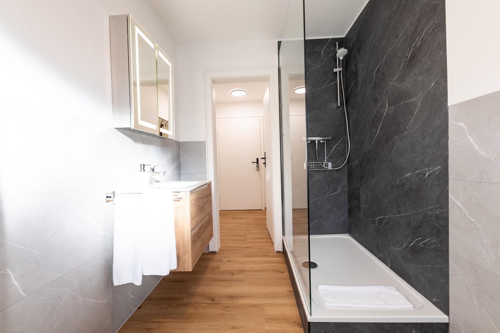 Badezimmer mit Dusche, Waschbecken und Spiegel