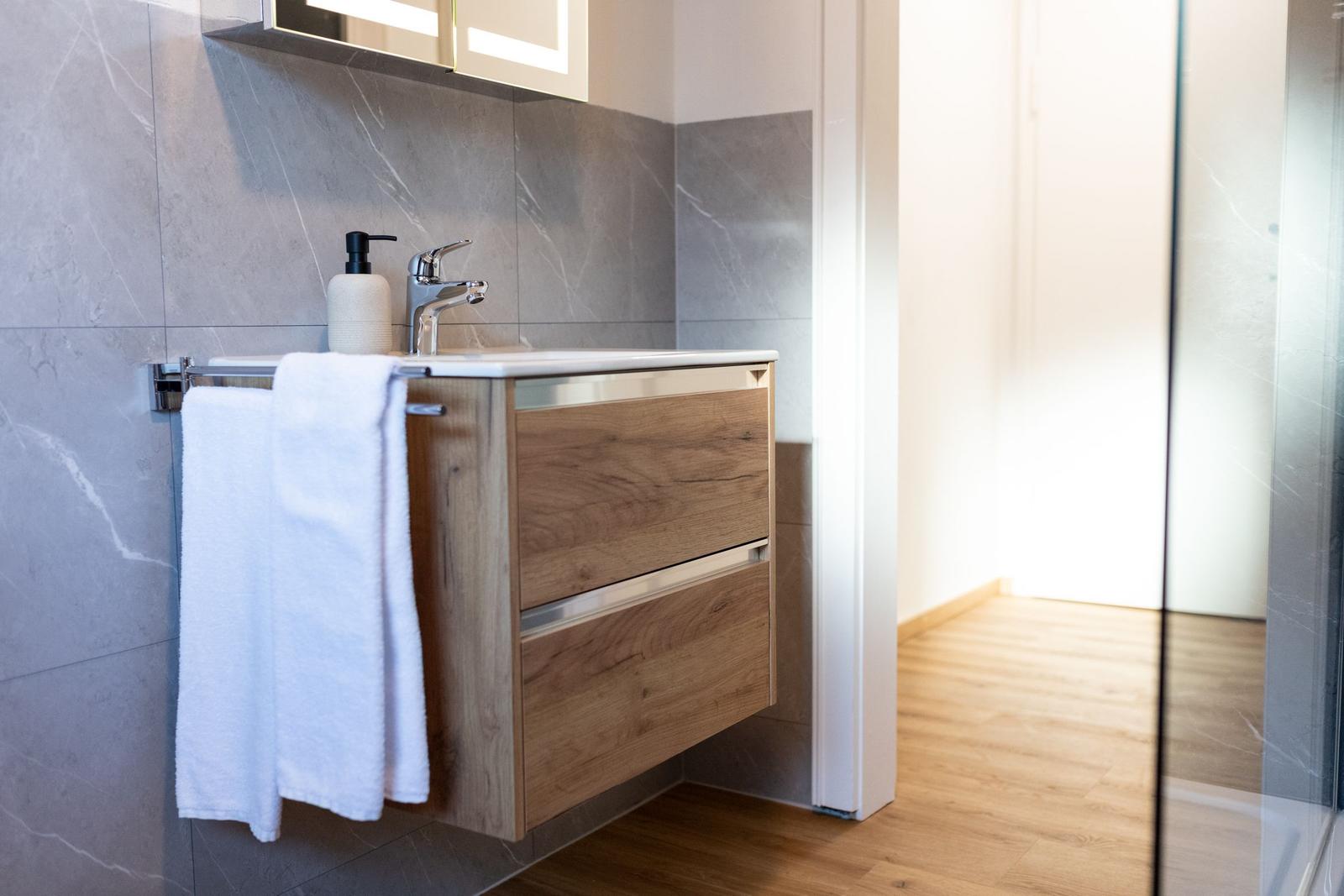 Badezimmer mit Waschbecken, Spiegelschrank und Duschabtrennung.