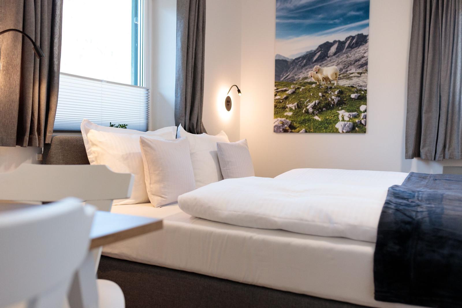 Schlafzimmer mit Bett, Fenster und Wandbild mit Schafen.