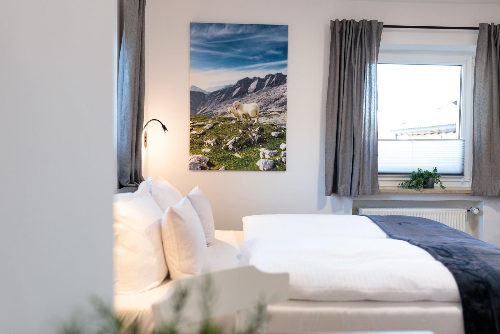 Schlafzimmer mit Bett, Wandbild und Fenster mit Vorhängen.