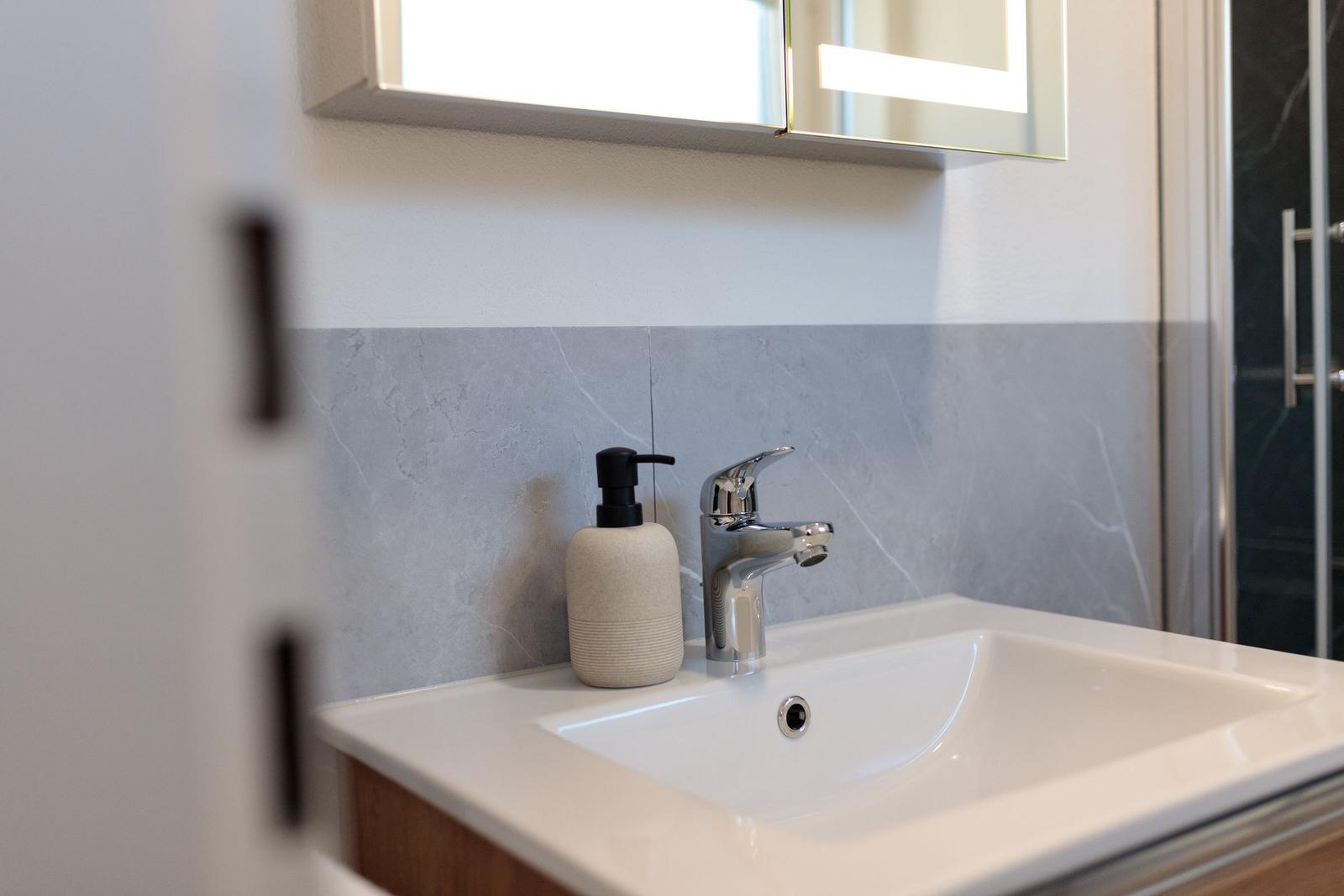 Waschbecken mit Spiegel und Duschbereich im Badezimmer