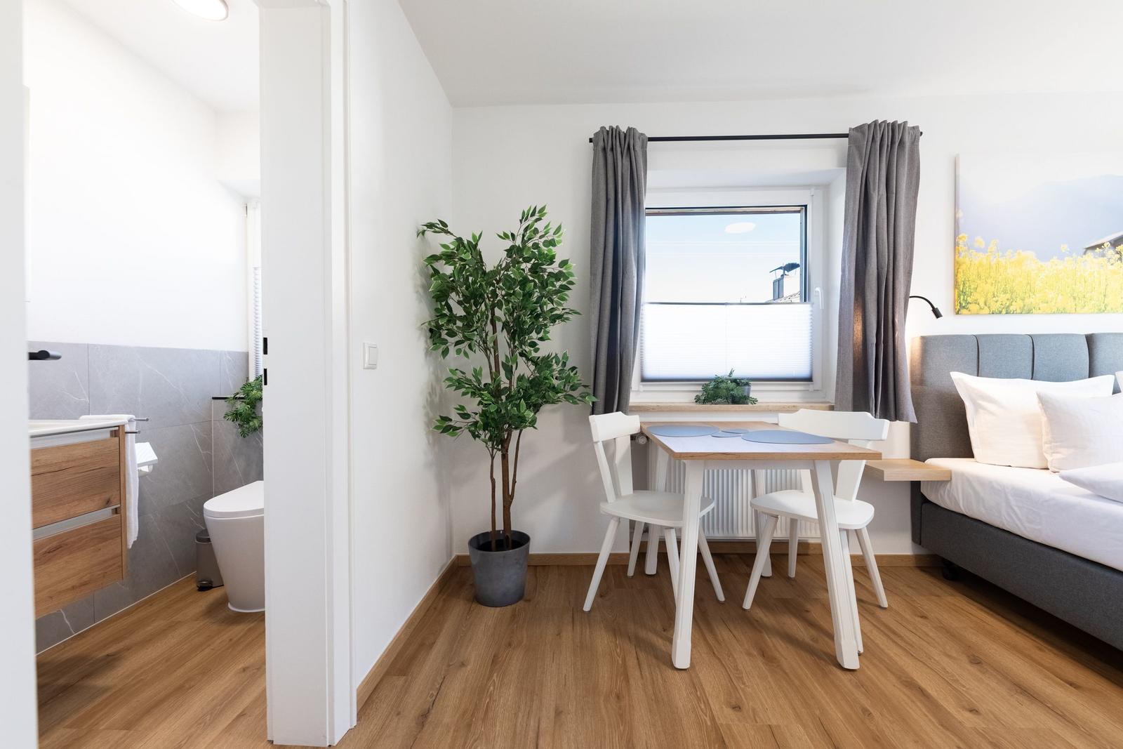 Schlafzimmer mit Bett, Tisch und Stühlen. Nebenraum mit Bad und Toilette.