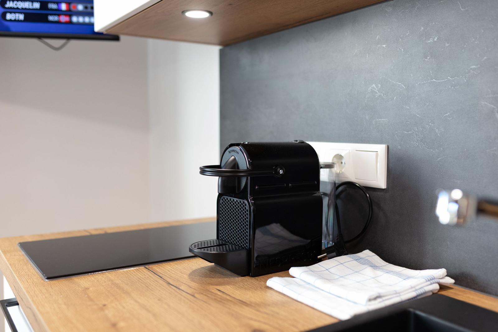 Küchenbereich mit Kaffeemaschine, Kochfeld und Handtuch auf Holzoberfläche.