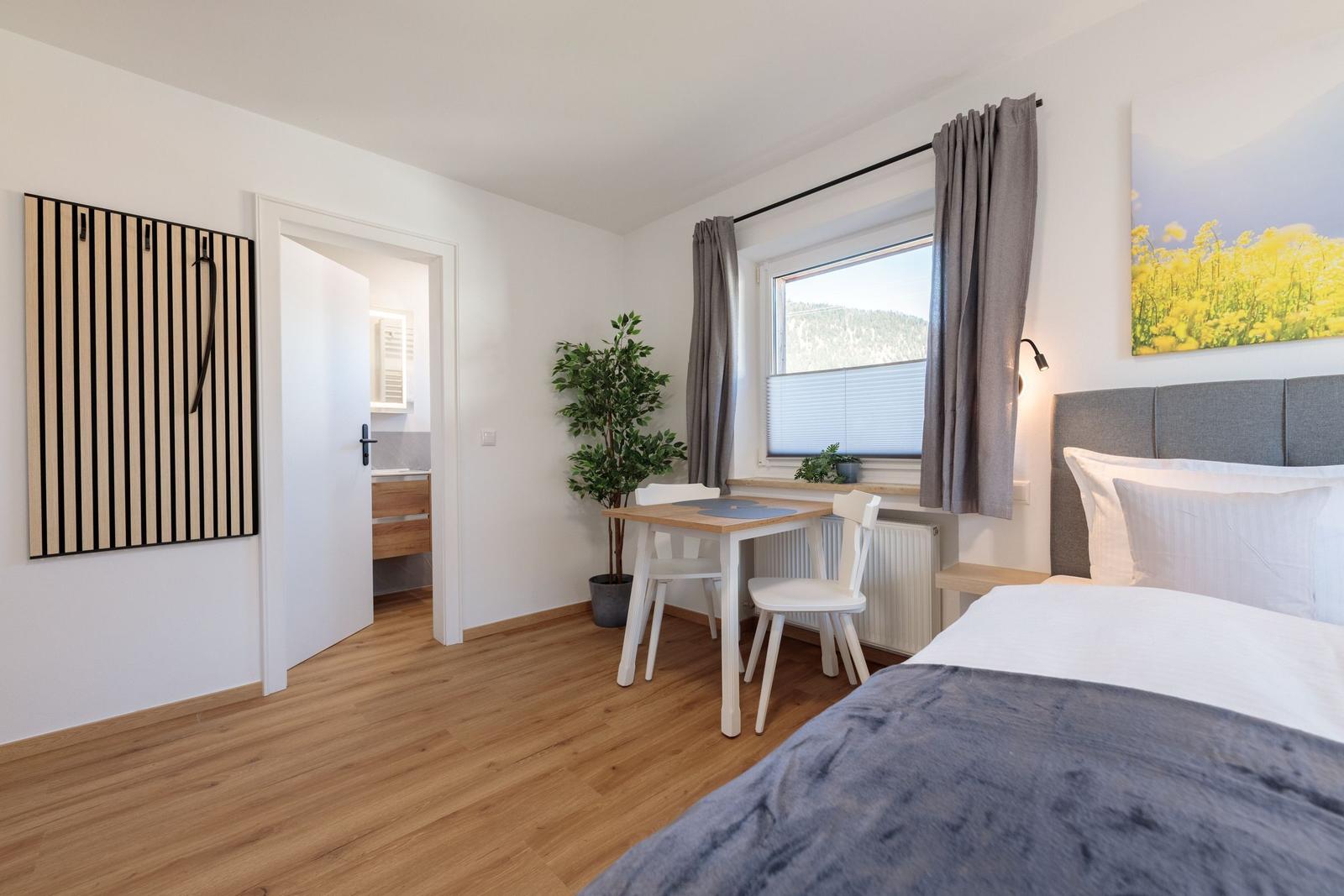 Schlafzimmer mit Bett, Tisch, Stühlen und Blick auf die Berge.