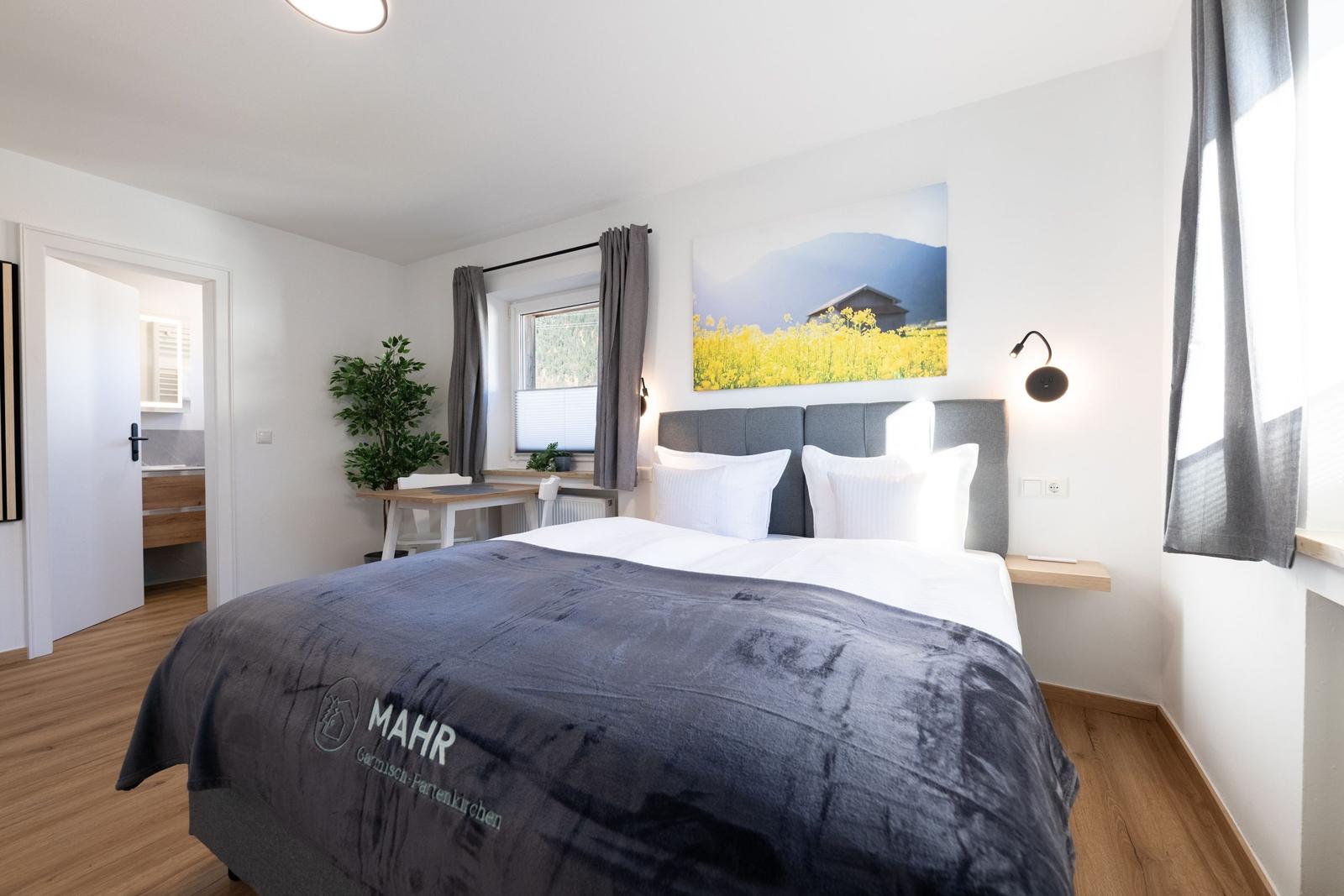 Schlafzimmer mit Doppelbett, Wandbild und Fenster. Blick in angrenzenden Raum.