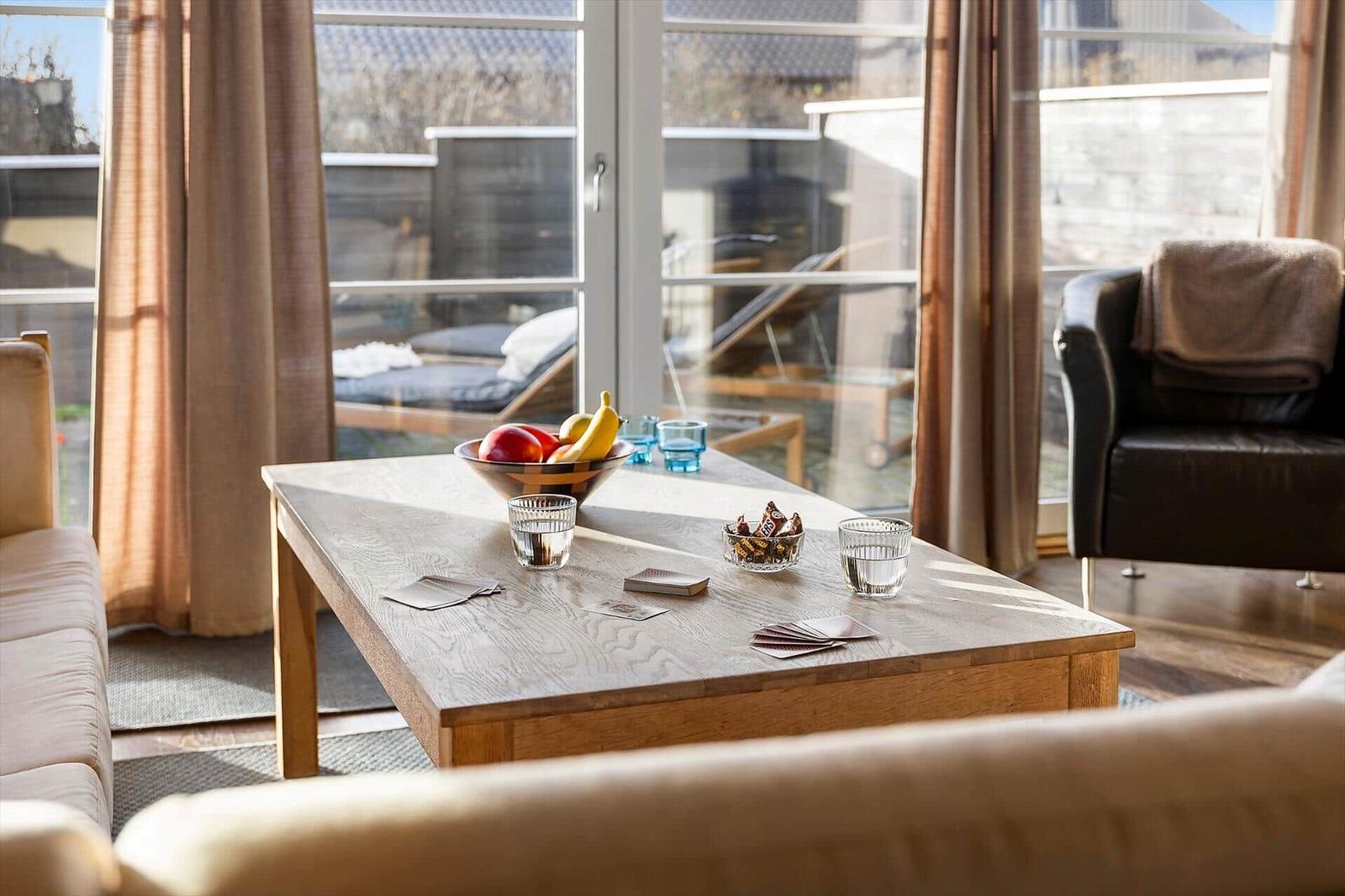 Ein Wohnzimmer mit Holztisch, Sofa und Blick auf eine Terrasse.