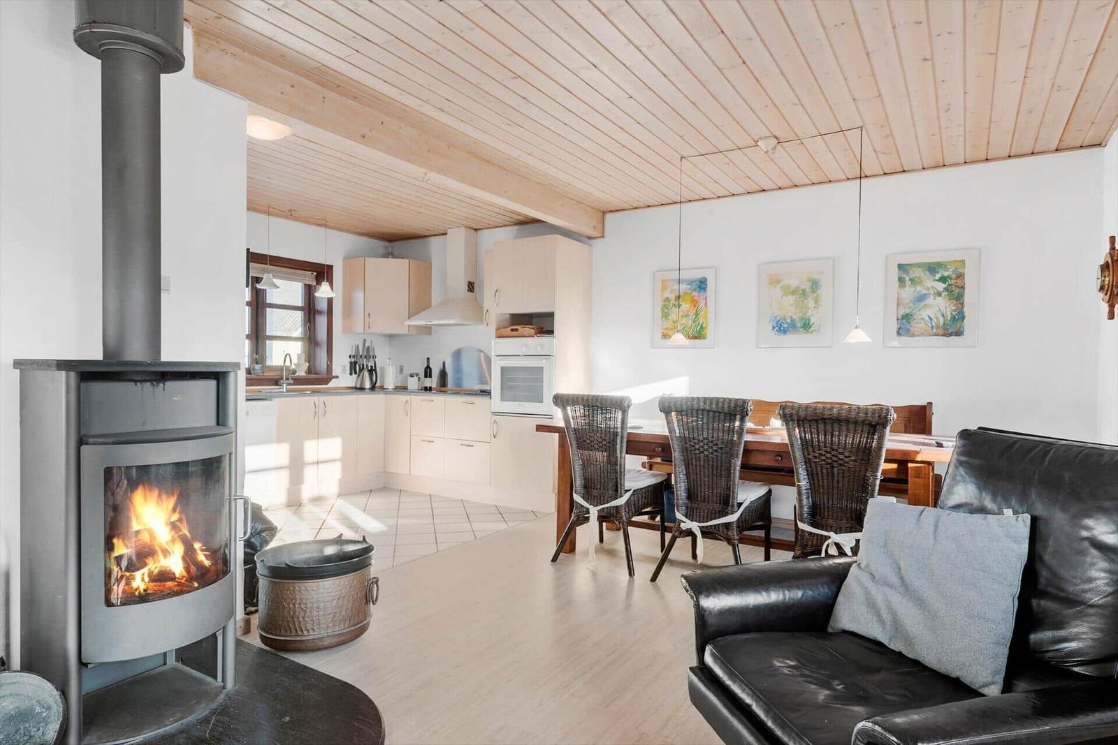 Kitchen, dining area, and living space with wood-burning stove and leather sofa.