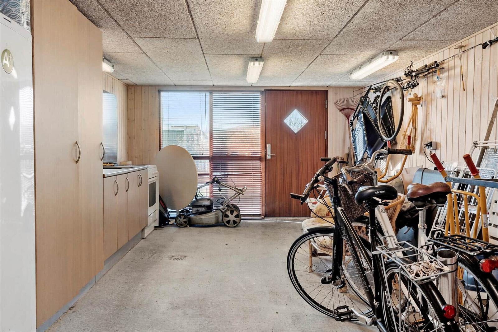 Vaulted room with kitchenette, bicycles, and garden tools on the wall.