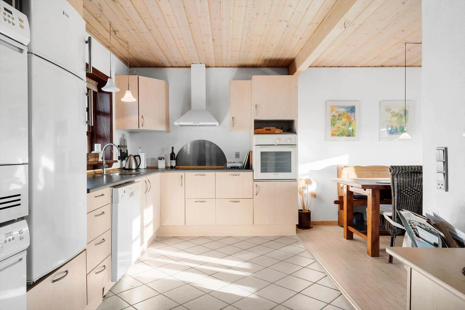 Kitchen with wooden ceiling, white appliances, and dining area with table and chairs.