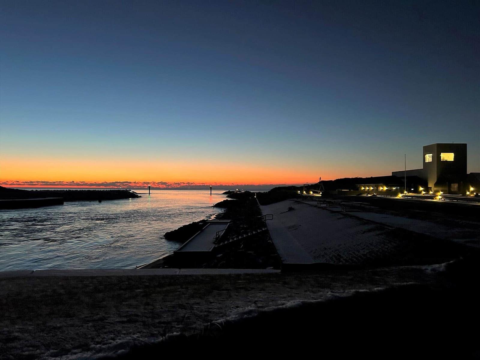 Sunset over water with lit building in the background