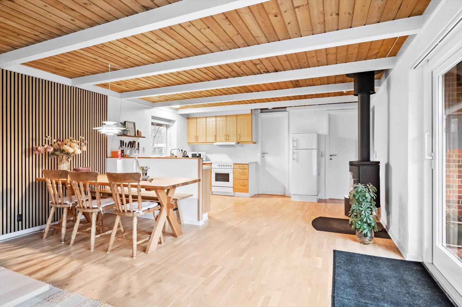 Wohnküche mit Holzboden, Essbereich und Kaminofen. Holzdecke und moderne Einrichtung.