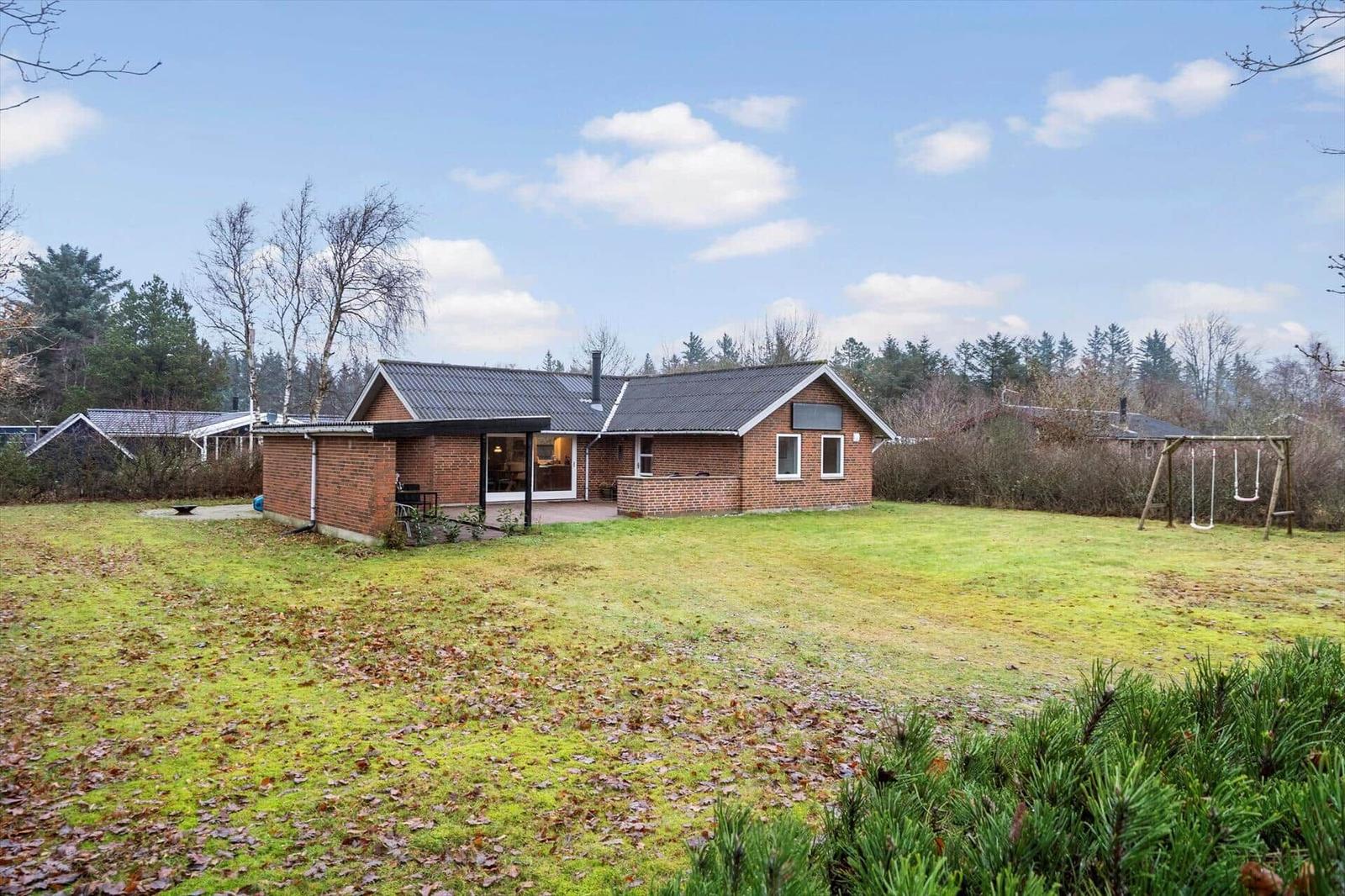 Ein Haus mit Garten und Spielplatz in einer ländlichen Umgebung.