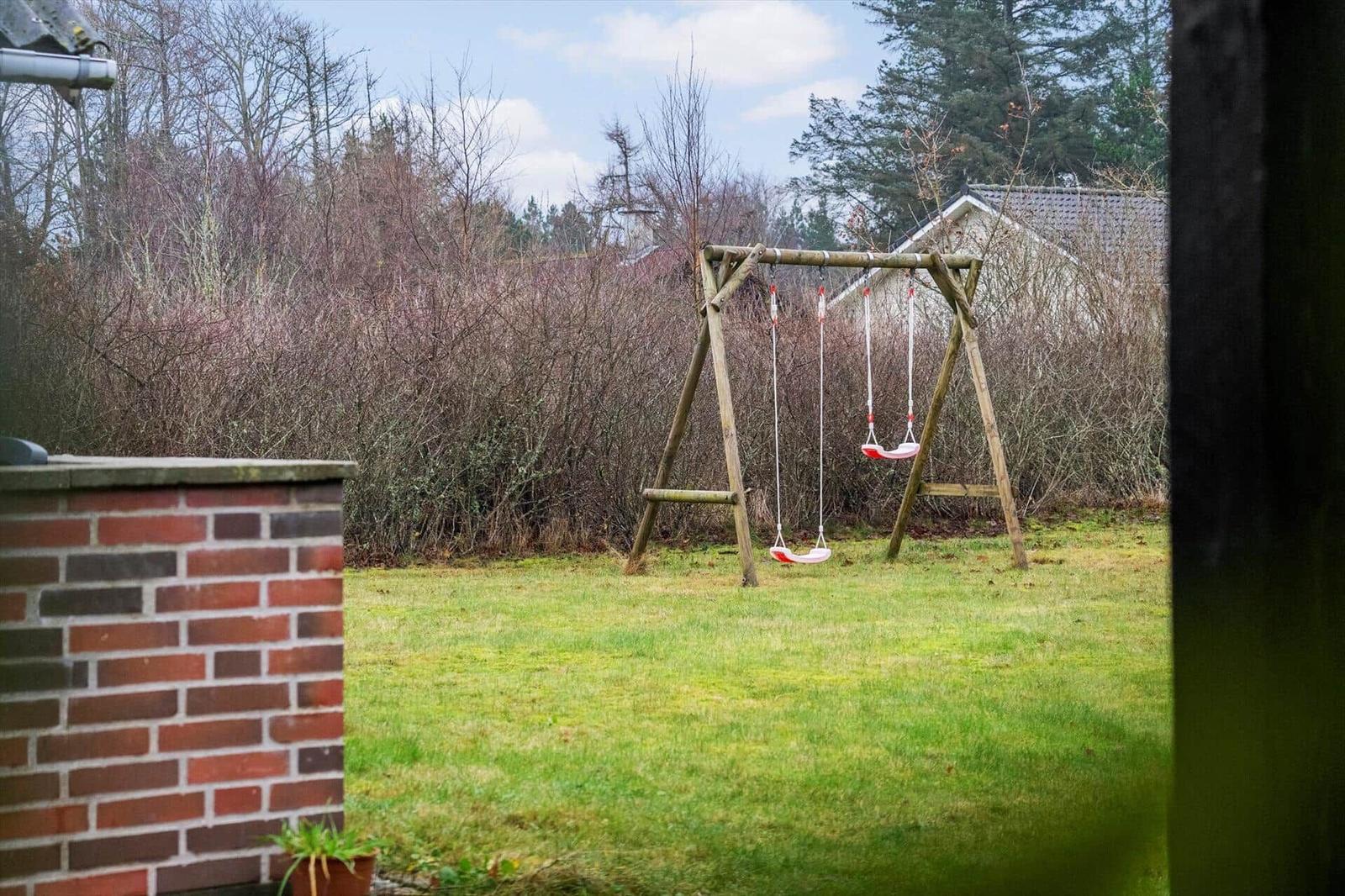 Hinterhof mit Schaukel, Grasfläche und Hecken. Blick auf angrenzende Häuser.