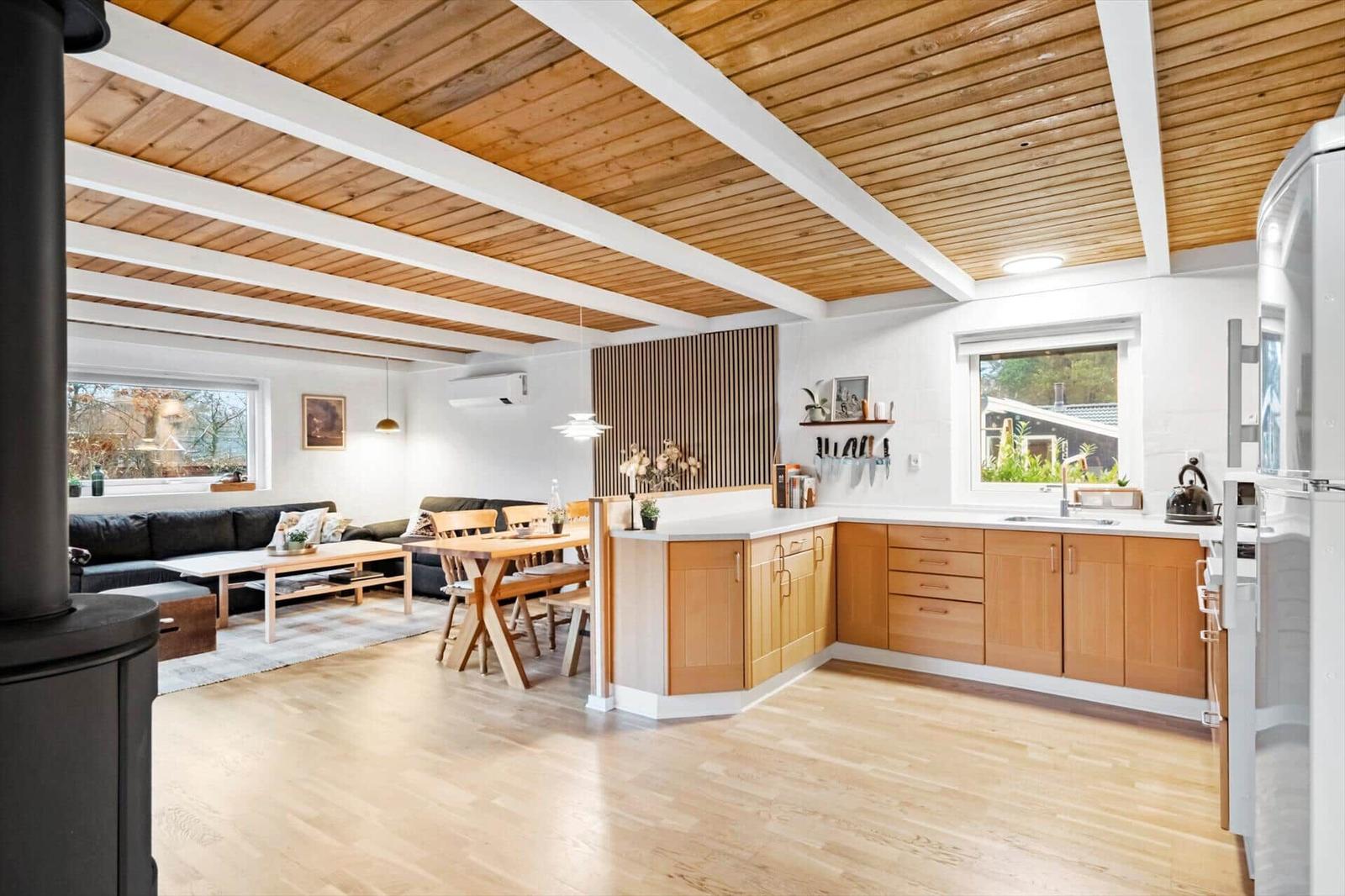 Küche mit Holzschrank und Essbereich. Wohnzimmer mit Sofa und Fenster.