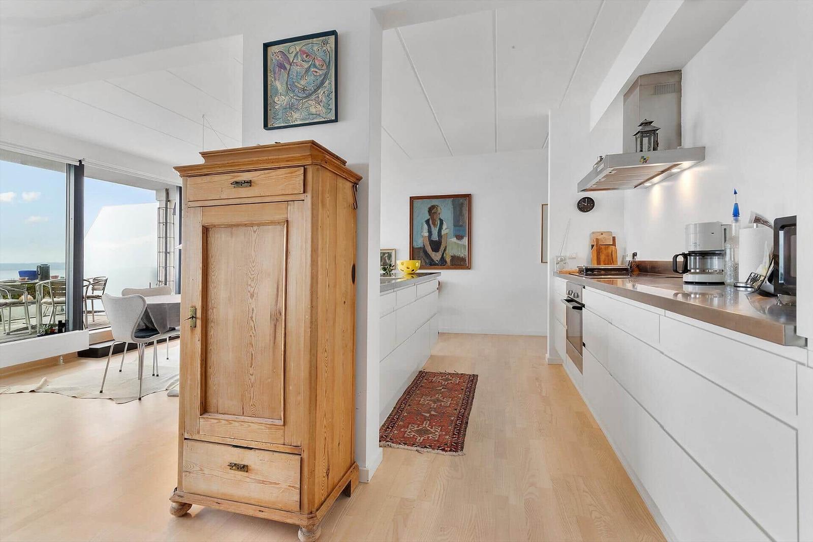 Kitchen with white cabinets and view to terrace with sea view.