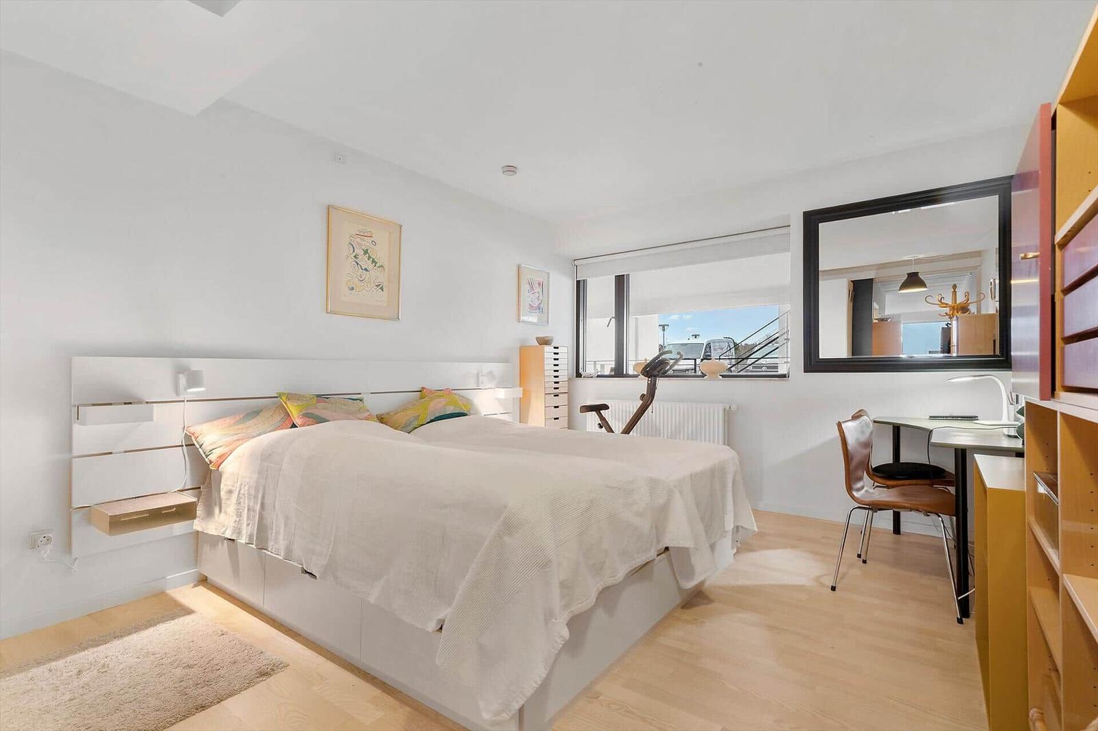 Bedroom with bed, desk, and mirror on the wall.