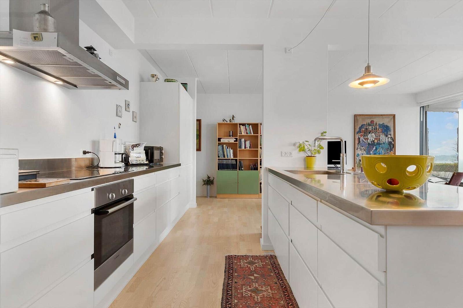 Kitchen with white built-in cabinetry, stainless steel countertop, and view to terrace.