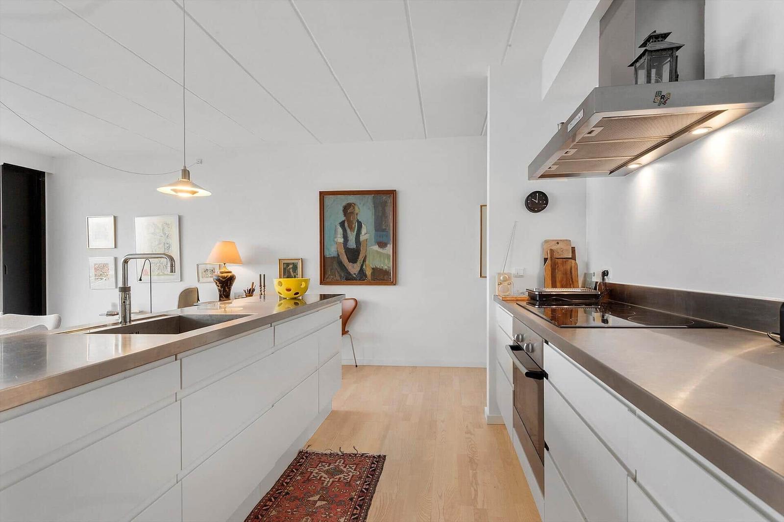 Kitchen with worktop, stove, and extractor. Wooden floor and wall pictures.