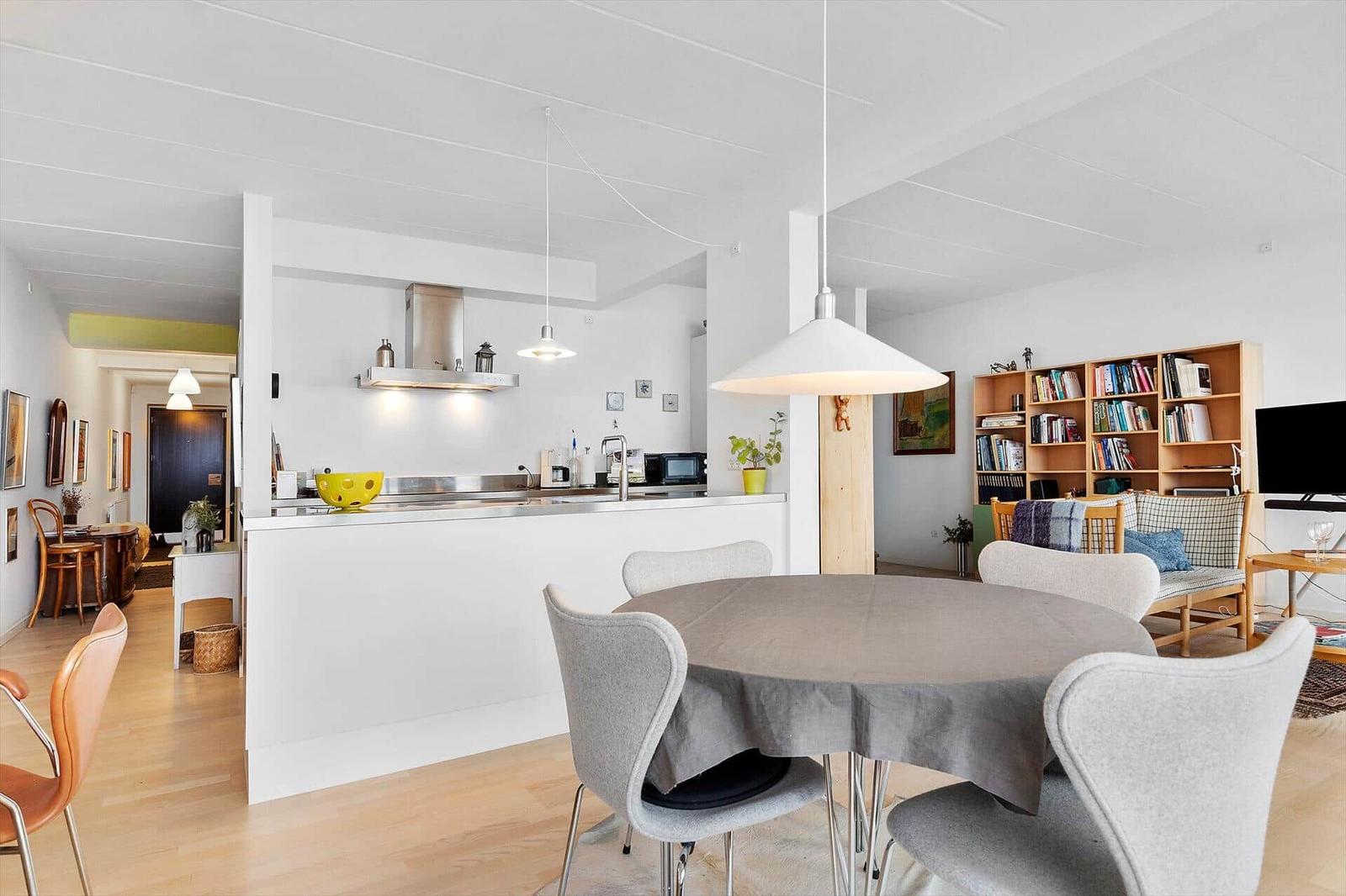 Dining area with round table and chairs. Kitchen and living room in background.