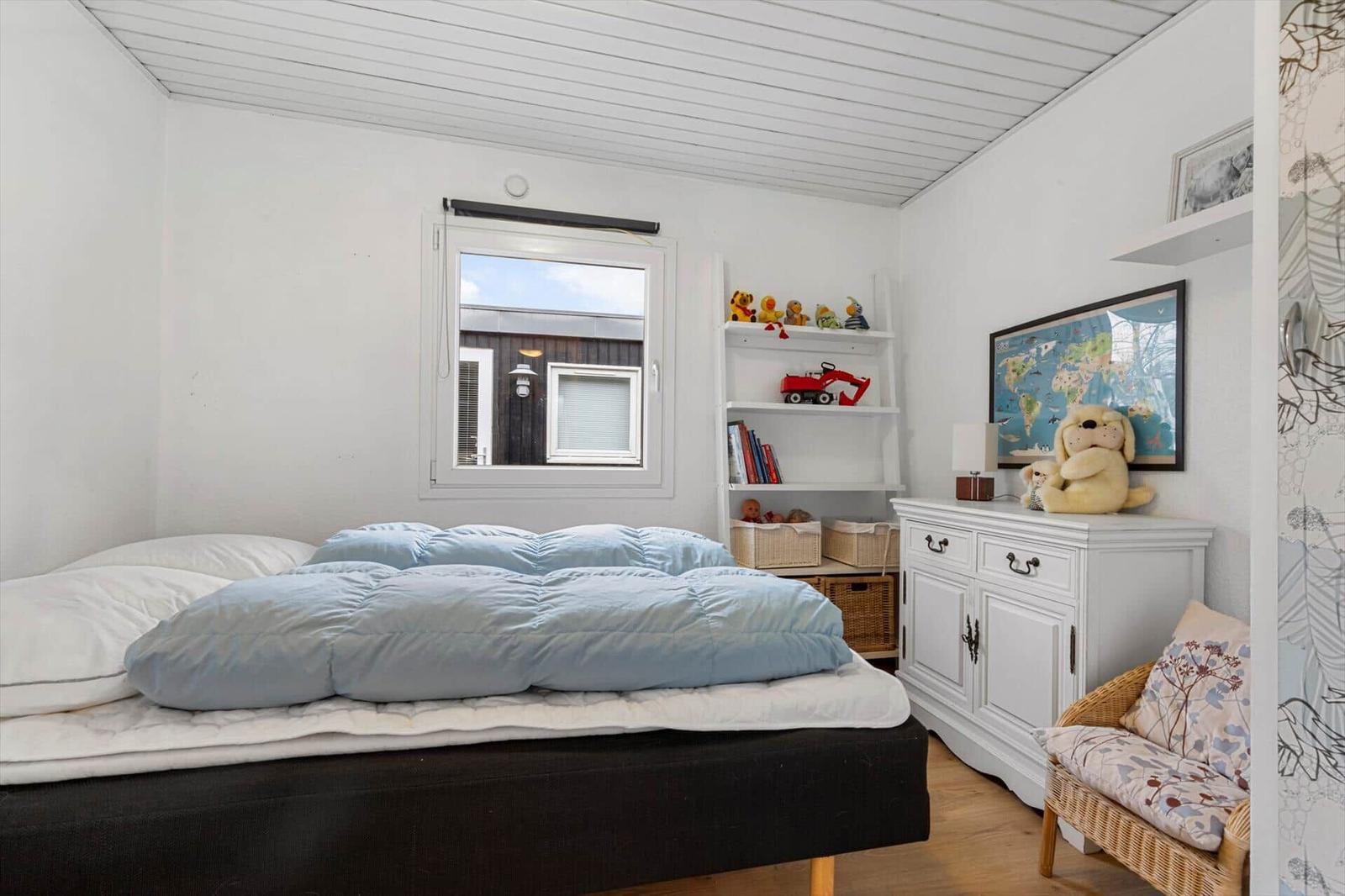 A bedroom with bed, dresser, shelf, and window. A world map is on the dresser.