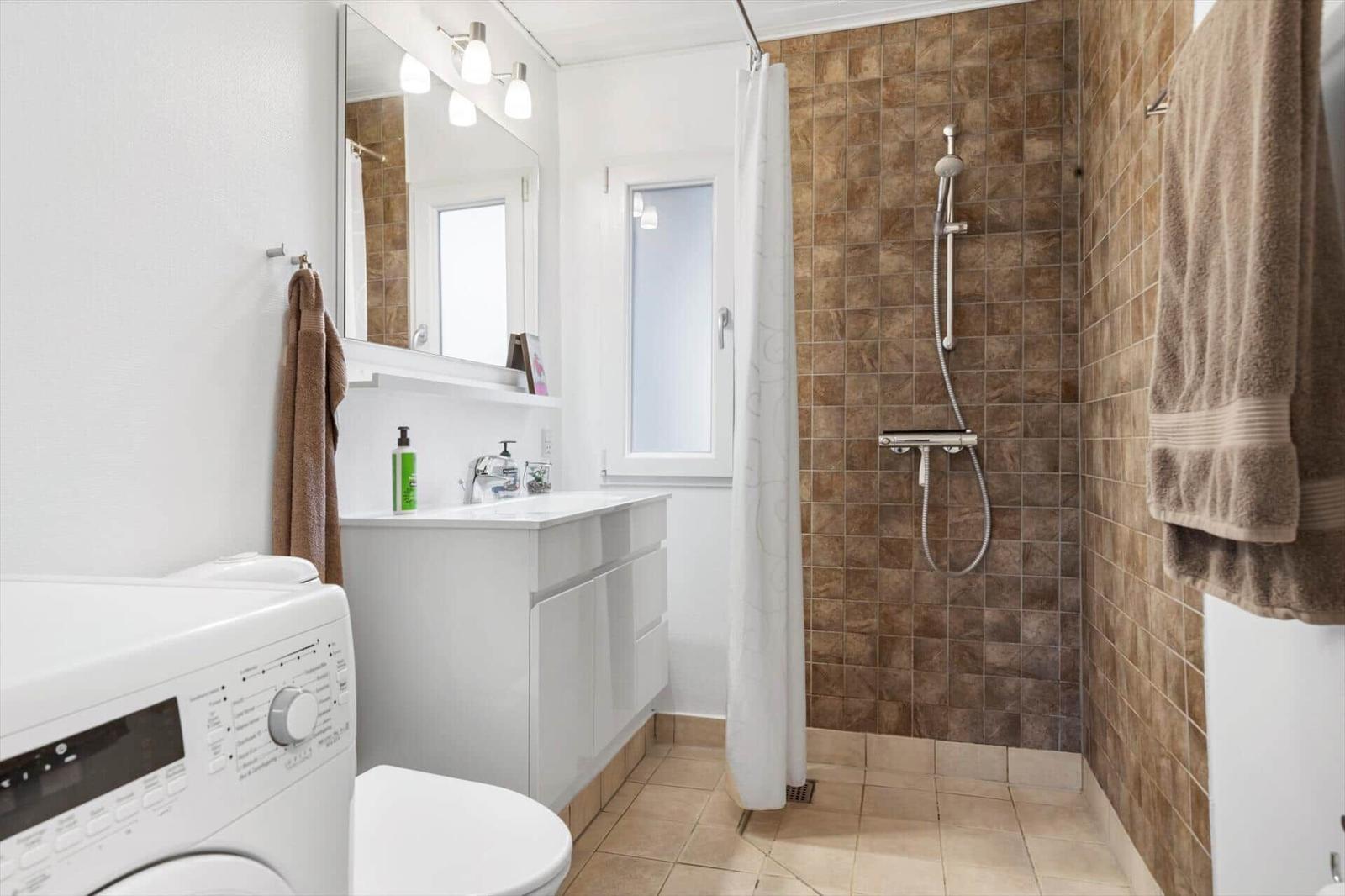 Bathroom with shower, sink, and washing machine.