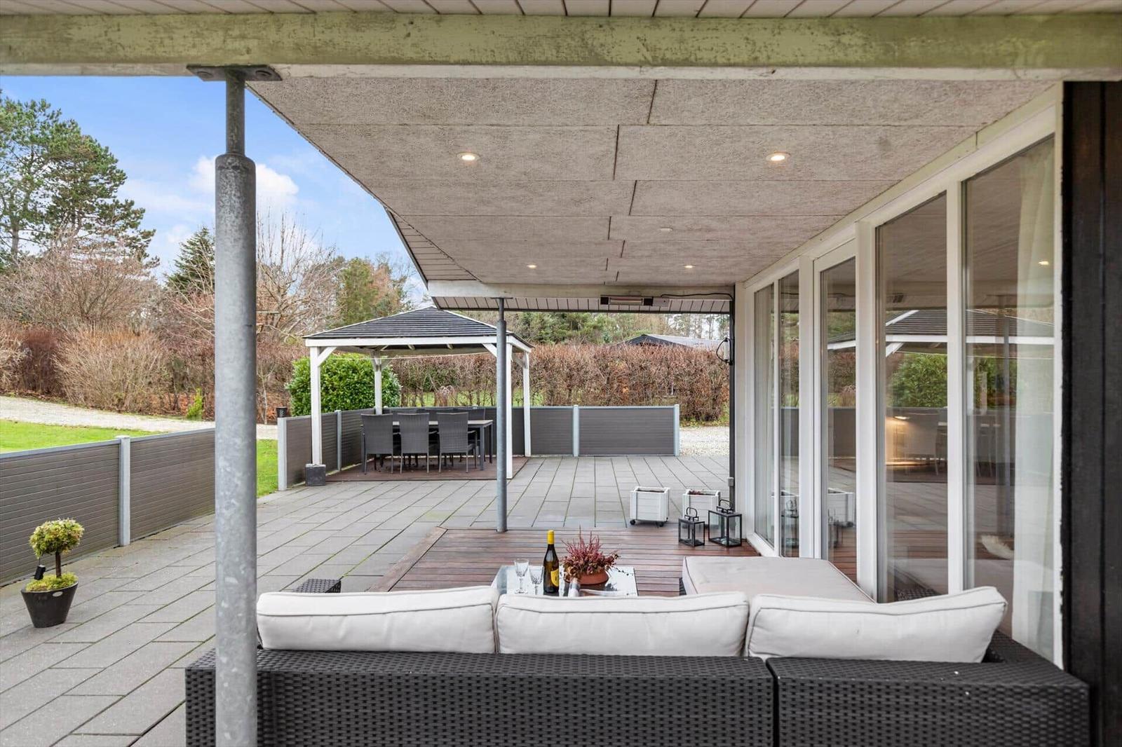 Terrace with seating area and gazebo. Glass doors and wooden decking.