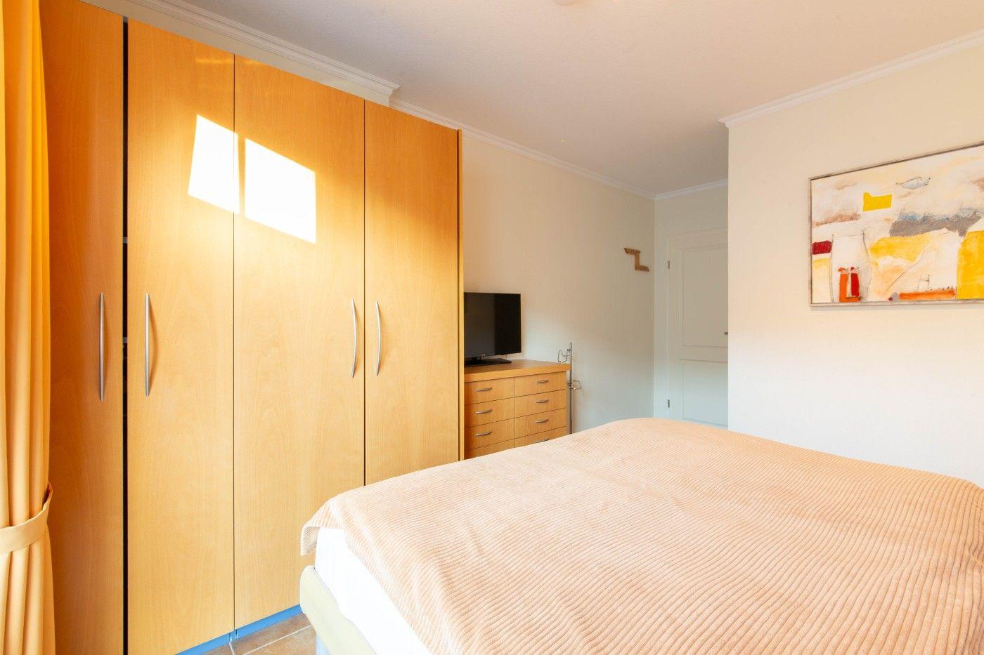 Schlafzimmer mit Bett, Kleiderschrank und Fernseher.