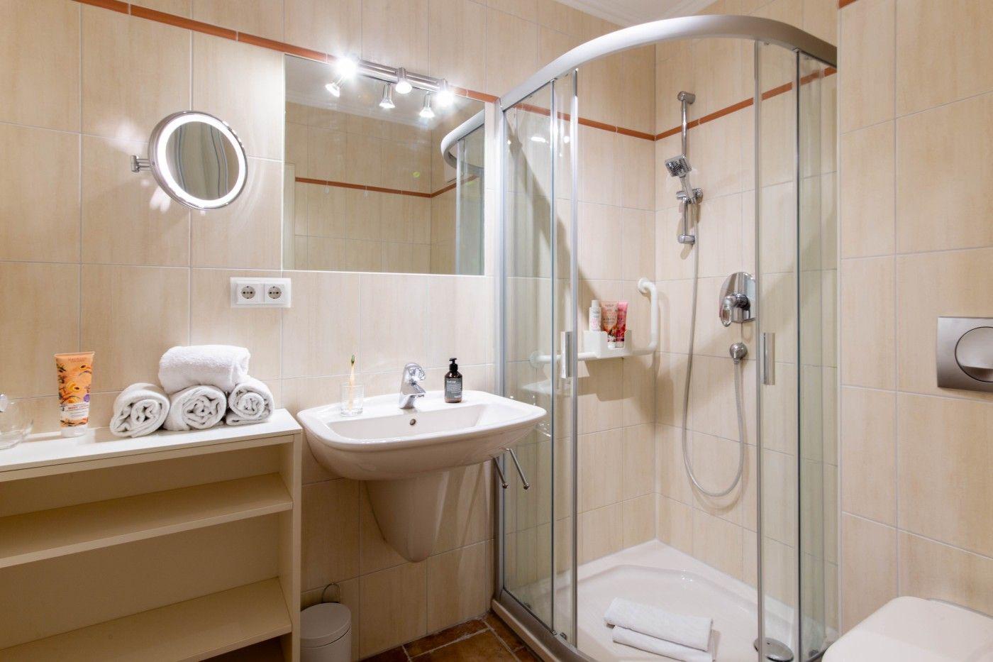 Badezimmer mit Dusche, Waschbecken und Spiegel