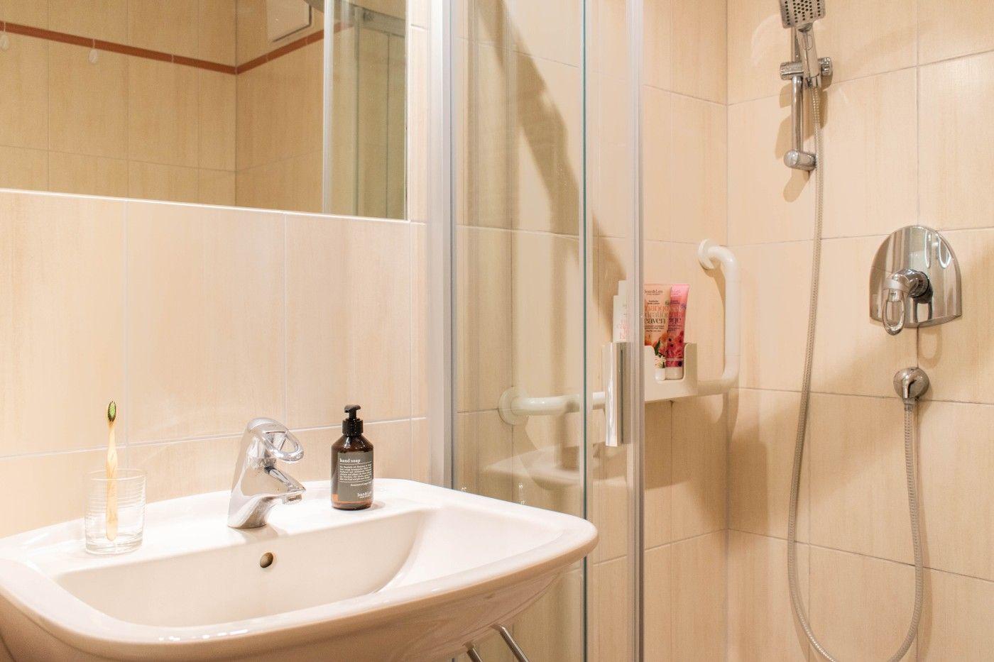 Badezimmer mit Dusche, Waschbecken und Spiegel. Handtücher und Pflegeprodukte sind vorhanden.