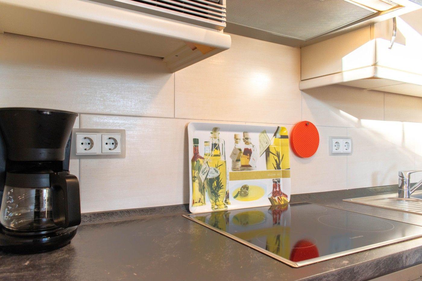 Küche mit Kaffeemaschine, Kochfeld und Dekoration.