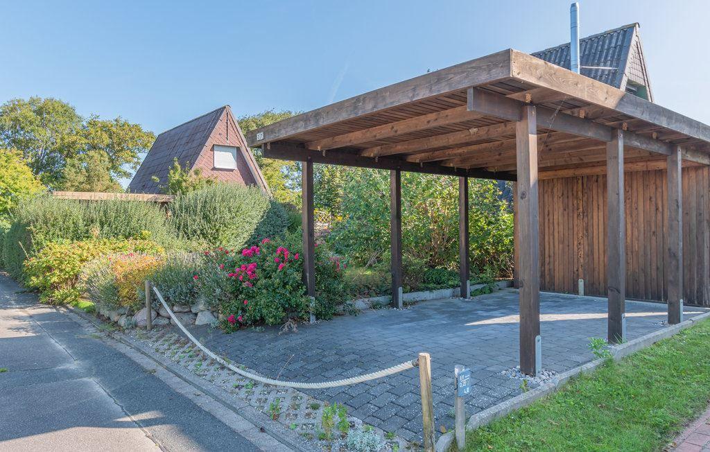 Holzüberdachung mit Sitzbereich, umgeben von Blumen und Grünflächen.