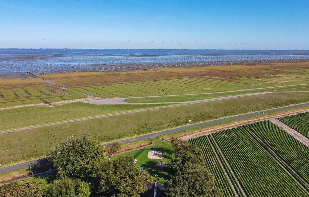 Weitläufiges Landschaftsbild mit Feldern, Wegen und Meeresufer unter klarem Himmel.