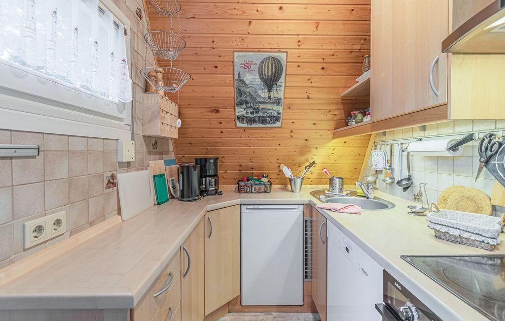 Küche mit Holzwänden, Arbeitsplatte, Spüle und Küchengeräten.